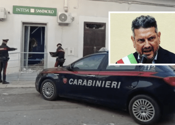 Roberto Nigro; sullo sfondo, un recente assalto alla banca Intesa del paese