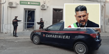 Roberto Nigro; sullo sfondo, un recente assalto alla banca Intesa del paese